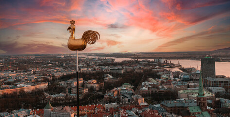 Beautiful aerial view of the city from above with a golden cock in the middle. Sunset time. © Oleg