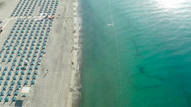 Aerial view of beautiful sea and beach with parasol at sunny day, seascape and hill mountain on backgrond, Simeri Mare, Calabria, Southern Italy
