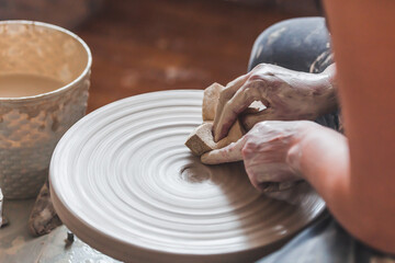 Hands of a potter girl at work on a potter's wheel.