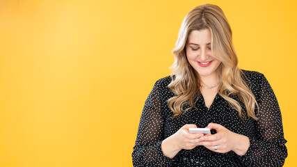Mobile communication. Gadget people. Body positive. Weight loss app. Happy smiling overweight plus size obese woman using phone isolated on bright orange copy space background.