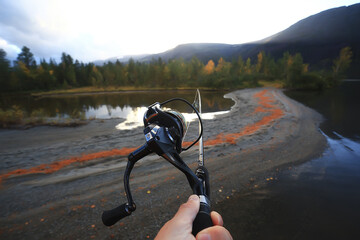 Fototapeta na wymiar spinning reel in hand fishing nature, abstract background, hobby vacation man