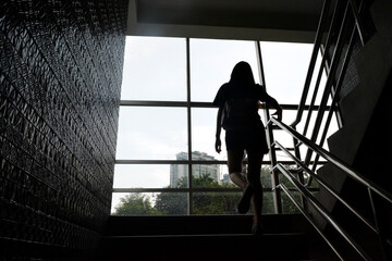 The young woman was stepping up the stairs of a tall building. silhouette