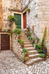 Fototapeta na wymiar Picturesque street in Trogir city with flower pots and fresh laundry