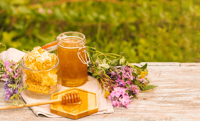 Fresh honey in a glass jar on a summer rural background. Floral fragrant sweet honey dessert, front view 