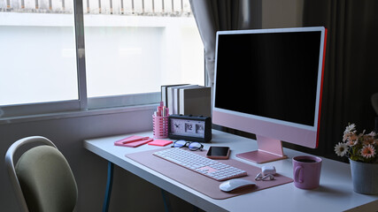 Designer workspace with computer and supplies on white table.