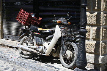 Alter abgenutzer weißer Motorroller oder Mofa steht an einer Straßenlaterne in Korca, Albanien