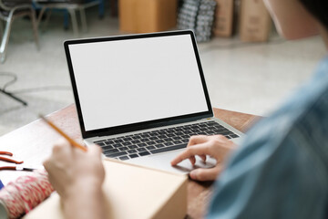 Online small business owner writing address on parcel box.