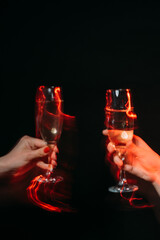 Naklejka na ściany i meble Corporate party. Holiday toast. Cheer greeting. Festive celebration. Female hands holding glasses of champagne long exposure defocused red light isolated black.