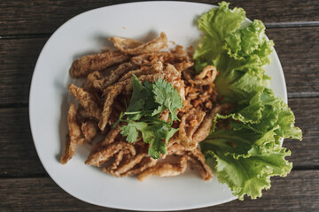 Thai crispy fish served in white dish and decorated with vegetable.