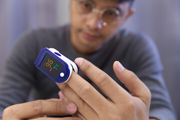Man measuring his own oxygen   Using a Fingertip Pulse Oximeter