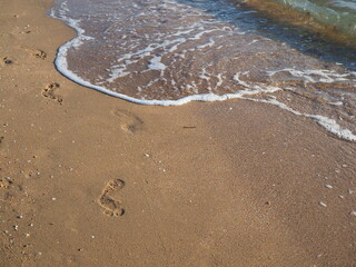 Human footprints on the sand beach,wave washes away the traces