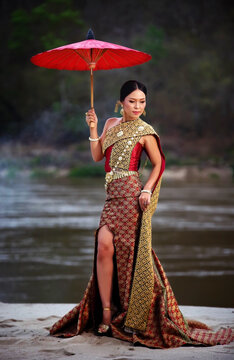 Beautiful thai wemen in the traditional dress with umbrella action portraid fashion photografe with local river background