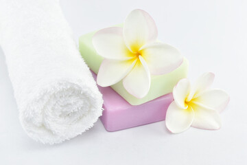 Beauty and fashion concept. white towels, natural soap and plumeria on white background.