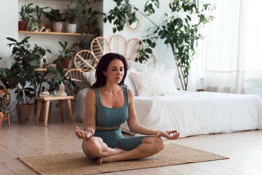 Woman doing yoga practice or meditation at home. Sitting on floor zen pose