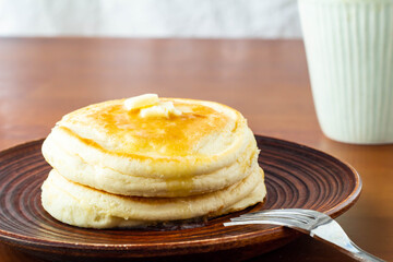 バターののったパンケーキとコーヒーの入ったカップ