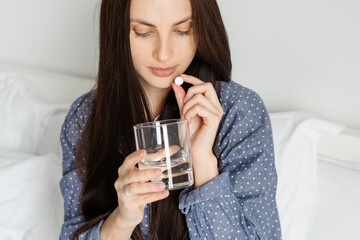 Young woman in pajama taking pill in morning