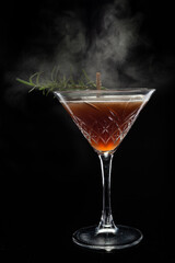 Alcoholic cocktail Cosmopolitan cocktail decorated with rosemary on martini glass and spray  on black background. Copy Space.