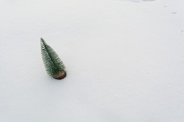 Plastic christmas tree on real snow with copy space. Winter holiday background