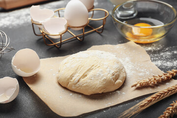 Fresh dough with ingredients for preparing bakery on dark background