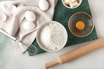 Fototapeta na wymiar Ingredients for preparing bakery and utensils on light background