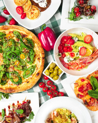 Shrimp pasta, carpaccio salad, spinach pizza, green olives and cherry tomatoes on the table. Italian concept, side view.