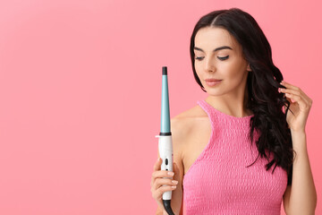 Obraz premium Beautiful young woman with curling iron on color background