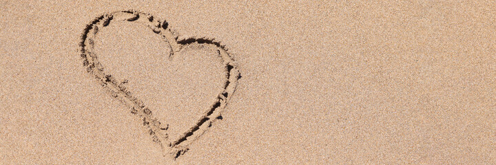 Drawn heart sign on wet sand on coastline