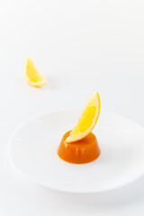 Pumpkin jelly and agar agar with orange on a white plate.
