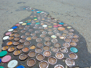Photo of a road surface with a decorative decoration made of lids from cans and bottles. Garbage for decoration and decoration.