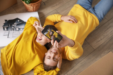 Young couple taking selfie in room on moving day