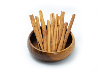 Cinnamon sticks in wooden bowl on white background.