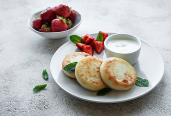 Cottage cheese pancakes, ricotta fritters on ceramic plate with  fresh strawberry.