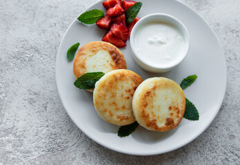 Cottage cheese pancakes, ricotta fritters on ceramic plate with  fresh strawberry.