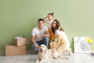 Fototapeta premium Happy family with dog and belongings near color wall