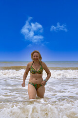 A woman in a swimsuit with white long hair comes out of the sea