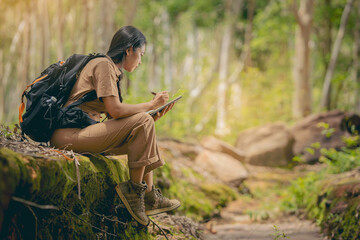 Biologist or botanist recording information about small tropical plants in forest. The concept of hiking to study and research botanical gardens by searching for information. - obrazy, fototapety, plakaty