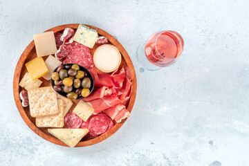 Obraz na płótnie Canvas Charcuterie and cheese platter, overhead shot with rose wine. Prosciutto di Parma ham, salami, blue cheese, olives and crackers, gourmet appetizers with a place for text