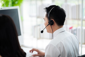 Team of call center staff in Asia wears headphones with a microphone. Smile while serving customers...