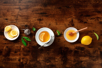 A cup of tea with lemons and honey, overhead flat lay shot on a rustic wooden background with copy space. Healthy organic citrus beverage for cold winter days