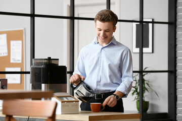 Naklejka na ściany i meble Young man pouring coffee into cup in office