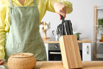Woman and stand with set of knives in kitchen