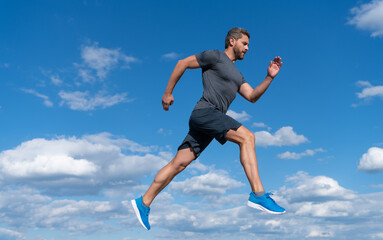 sportsman with muscular body running in sportswear outdoor on sky background, healthy lifestyle.
