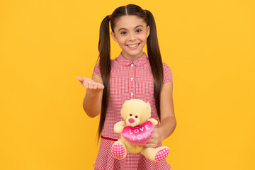 happy child presenting bear toy gift on yellow background, birthday