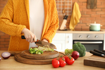 Woman cutting cabbage in kitchen
