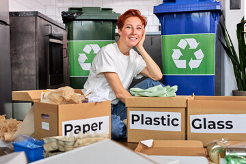 Optimistic young caucasian lady in casual wear sorting waste, using containers with different kind of garbage, millennial eco-volunteer woman enjoying trash recycling, indoors. Copy space.