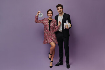 Joyful pretty lady in pink mini dress and black shoes posing on one leg with gorgeous young man...