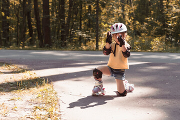 cute child girl in protective sportswear rollerblading.