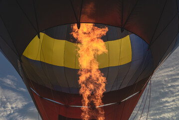 Naklejka premium Hot flame from a gas burner light up inside of a hot air balloon at evening.