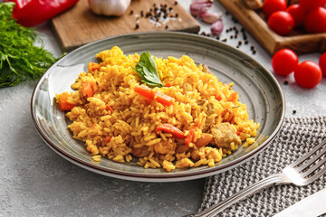 Plate with tasty pilaf on light background