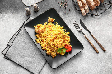 Plate with tasty pilaf on grunge background
